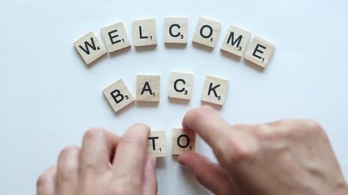 composing phrase welcome back to with wooden letters
