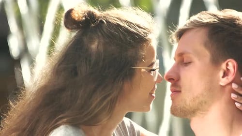 Young Couple Sharing Kiss in Sunny Urban Setting
