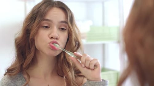Young Woman Brushing Teeth in Bright Bathroom