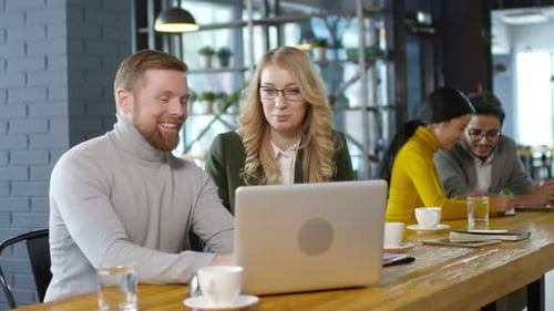 Caucasian Colleagues Discussing Project on Laptop in Cafe