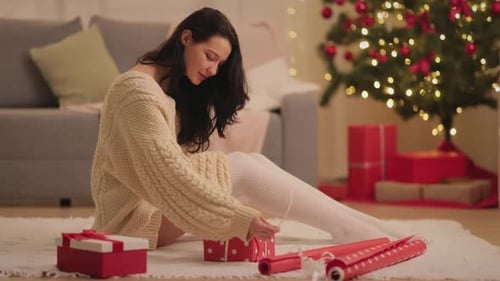 Young Woman Wrapping Christmas Presents at Home