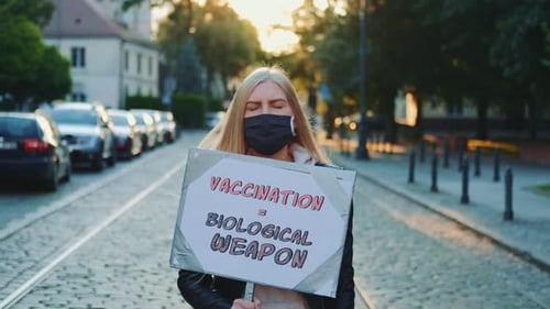 Woman Holds Sign in Cobblestone Street
