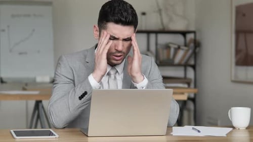 Stressed Businessman with Headache Working on Laptop