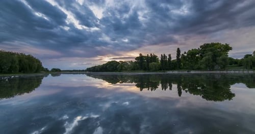 Zeitraffer eines schönen bewölkten Sonnenaufgangs in einem See mit Reflexion