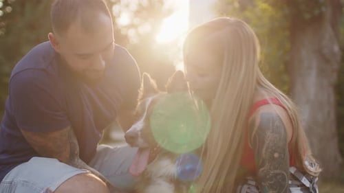 Close Up of Young Couple Petting Their Dog While Having a Walk in Park