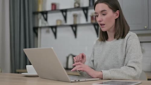 Excited Woman Cheers at Laptop in Home Setting