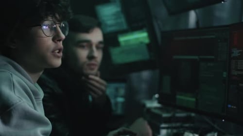 Hackers masculinos usando computadores e falando