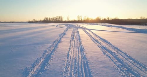 Aerial of Winter Field with Tracks at Sunrise