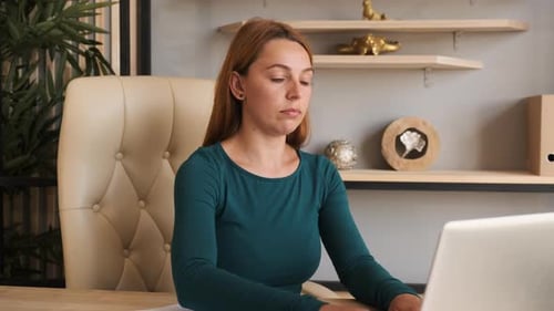 Woman Stretching at Desk in Office