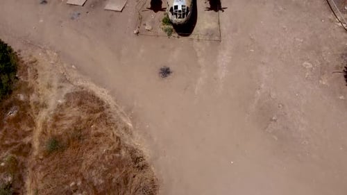 aerial turning and rising shot of an old dismantled army plane monument placed on an empty dirt fiel