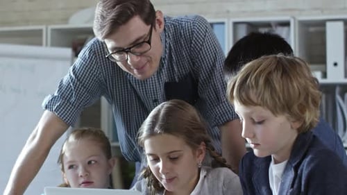 Children Collaborating on Laptop with Teacher Guidance