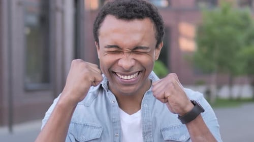 Man Smiling and Celebrating Success in Urban Setting