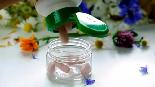 Pills Being Poured Into a Jar with Flowers