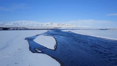 Luftaufnahme eines blauen Flusses in einer verschneiten Landschaft