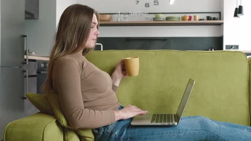 Young Woman Working on Laptop with Coffee at Home
