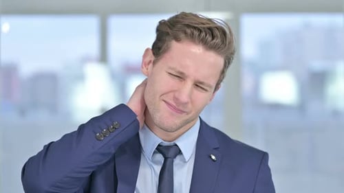 Young Adult Business Man Rubbing Neck in Pain