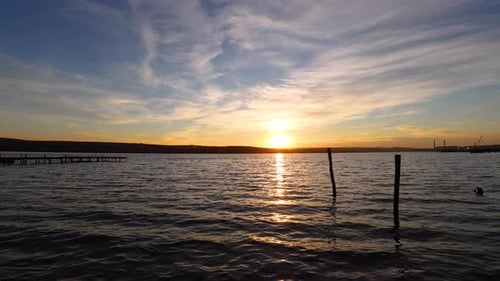 Sunset Over Still Lake with Wooden Posts