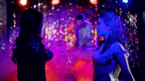 Silhouetted Women Dancing at Nightclub Party with DJ