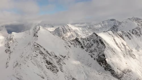 Snowy Mountain Summit with Blue Sky and White Clouds in Background