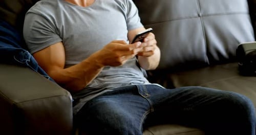 Young Man Relaxing at Home with Mobile Phone