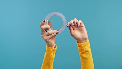 Mains féminines avec ruban adhésif sur fond bleu