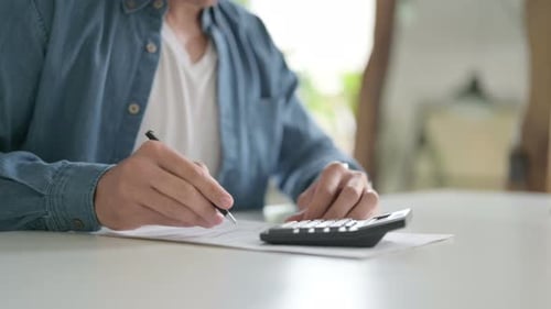 Calculating Figures at Office with Calculator and Pen
