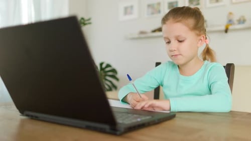 Girl Doing Homework at Table with Laptop