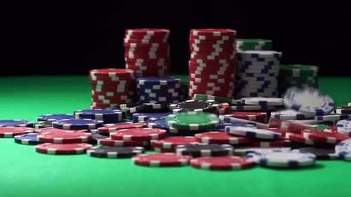 Stack of Poker Chips Lies on a Green Table and Some More of Them Fall in Slowmo