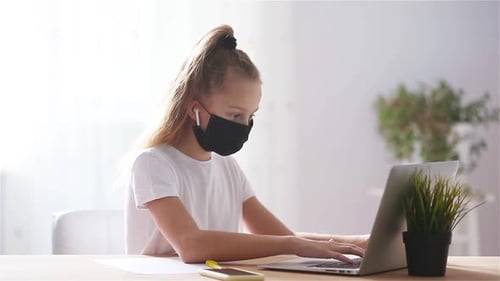 Child Working on Laptop Computer Wearing Face Mask