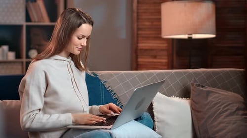 Woman Comfortably Using Laptop on Couch Indoors