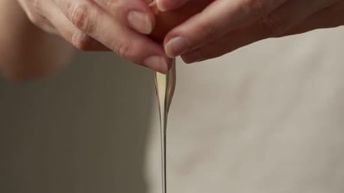 Nahaufnahme einer Frau, die in einer Bratpfanne ein Ei bricht, um Eier in der Küche zu kochen