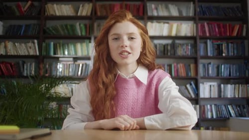 Friendly Woman Talking to Camera in Front of Bookshelf
