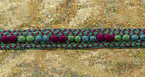 Motif de couleur tricoté sur un tissu brillant doré avec des paillettes en gros plan