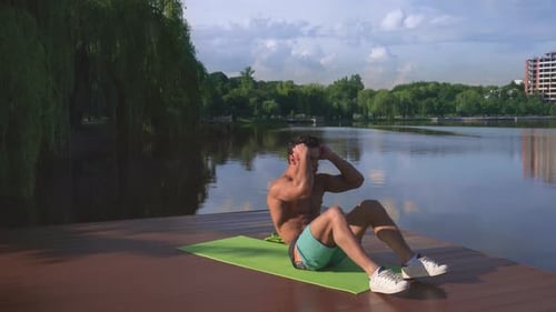 Aktiver starker Mann macht Bauchmuskelübungen am hölzernen Seesteg