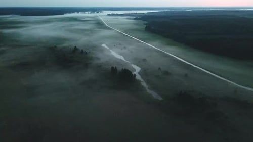 Foggy dawn in the countryside. Foggy river valley and rising sun. Aerial photography.