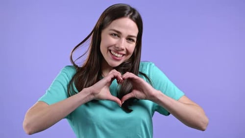 Woman Makes Heart Shape with Hands and Smiles