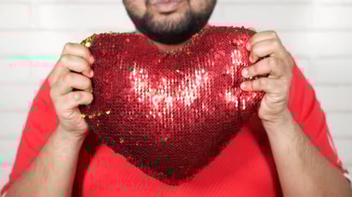 Man holds sequined red heart cushion