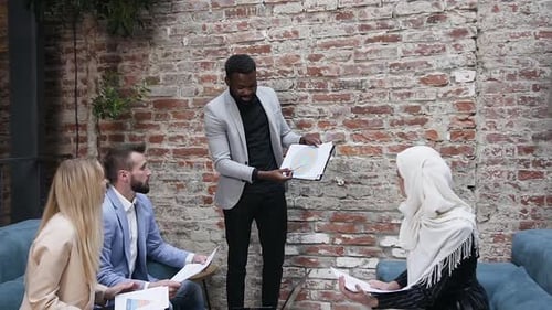 Pretty Muslim Businesswoman with Her Male and Female Business Partners Sitting on the Office