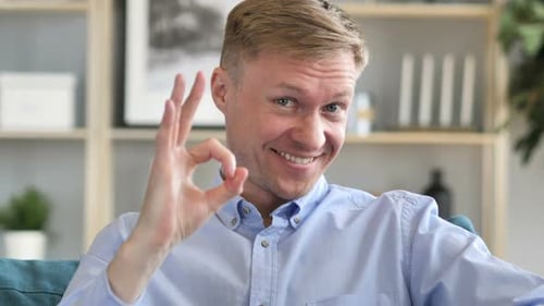 Man Gesturing Okay Sign and Smiling Indoors