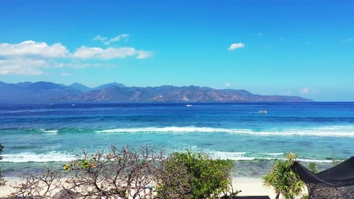 Amazing seascape with white waves of blue azure sea, bordered by high mountains on a bright sky back