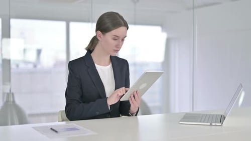 Hardworking Young Businesswoman Using Tablet in Modern Office
