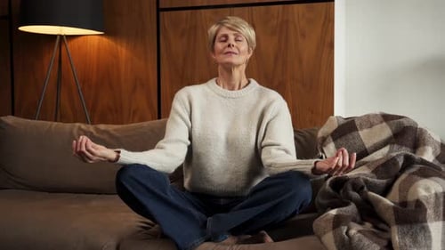 Woman Meditating Calmly on Sofa in Living Room