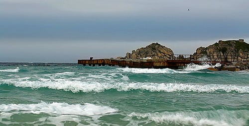 Waves Crashing on Rocky Shoreline Under Gray Sky