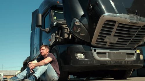 Man Sitting at Semi-Truck Using Cell Phone
