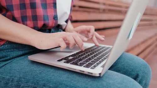 Gros plan des mains d'une femme travaillant à distance sur un ordinateur portable