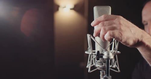 Sound engineer working in a recording studio with a sound console and microphones