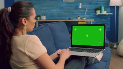 Woman Using Laptop with Green Screen at Home