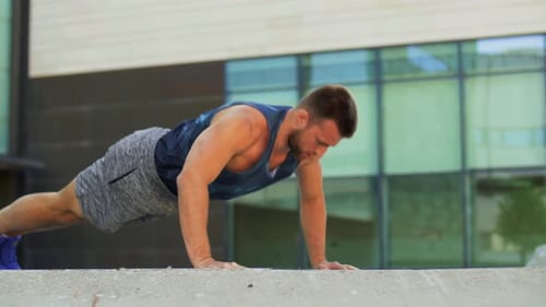 Joven haciendo flexiones en la calle de la ciudad
