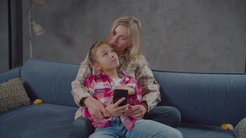 Woman and Child on Blue Couch with Phone