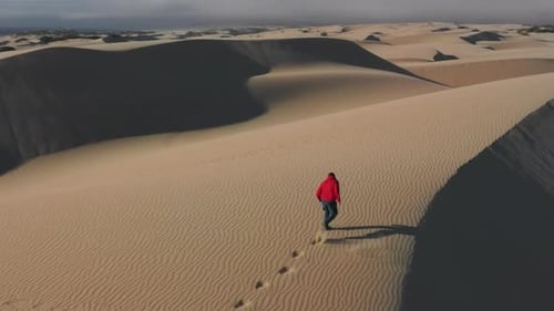 Un hombre corriendo hace ejercicio al aire libre en dunas de arena profunda, imágenes aéreas de deportes en el desierto